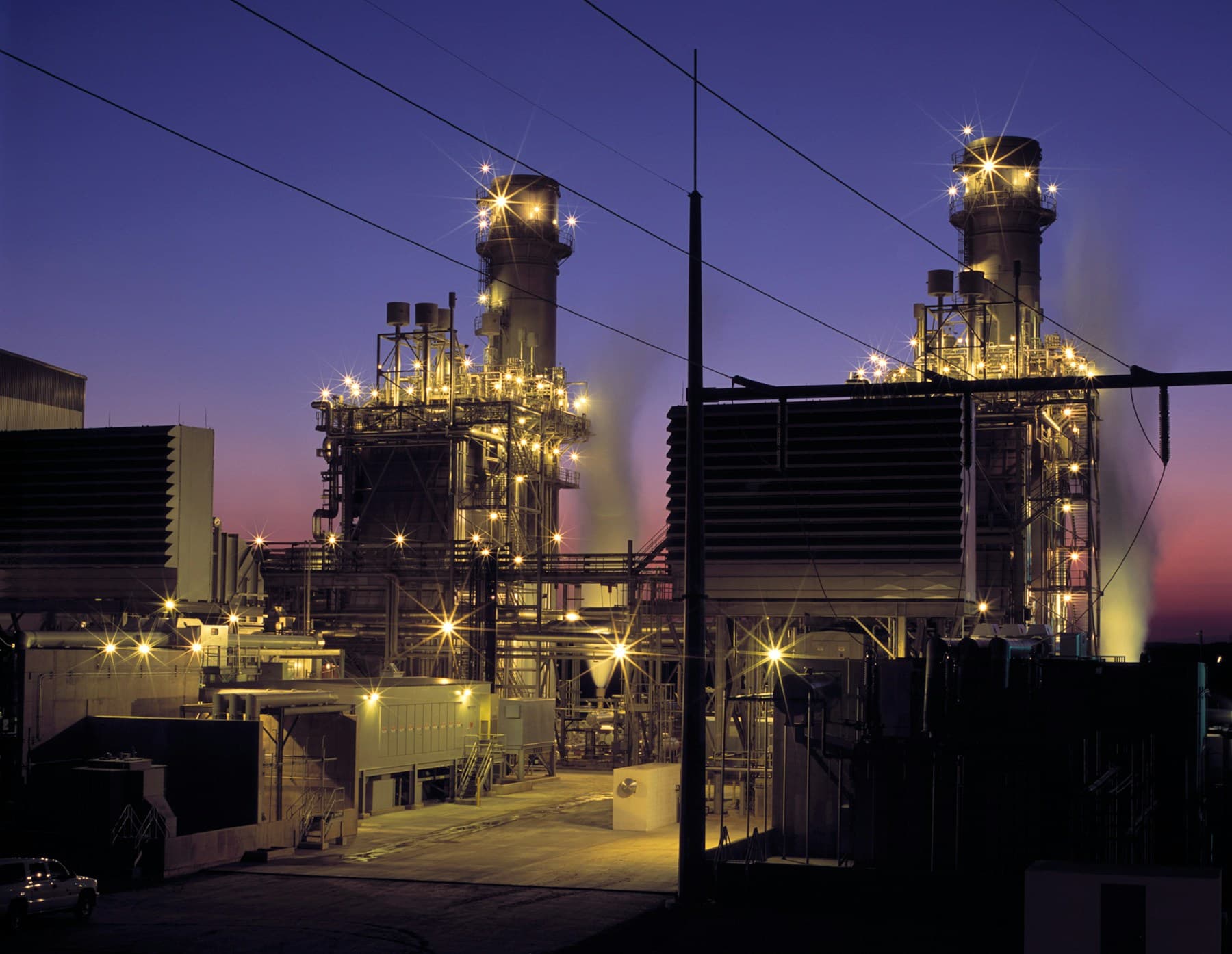 Combined-cycle gas power plant lit at dusk
